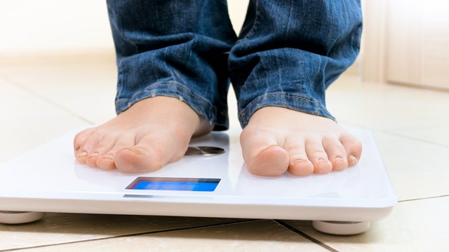 Closeup photo of young woman standing on digital scales
