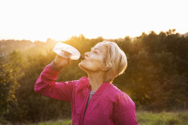Senior woman drinking water after run outdoors