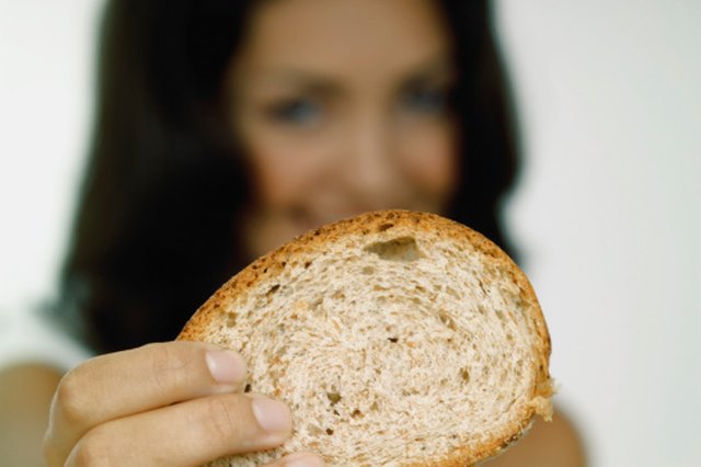 Young woman holding a piece of bread close-up, selective focus, focus on bread