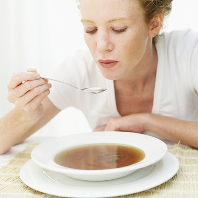 Young woman blowing a spoonful of hot soup