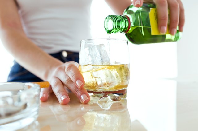 Young woman filling a glass of whiskey