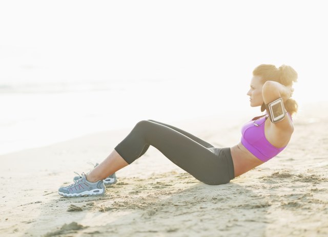 fitness young woman doing abdominal crunch on beach