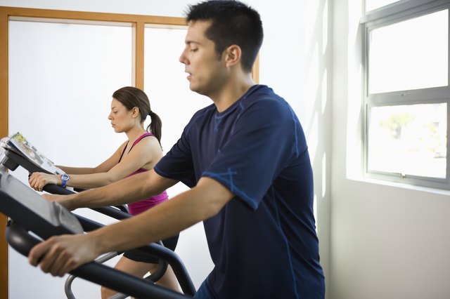 Young couple working out on elliptical machines in gym