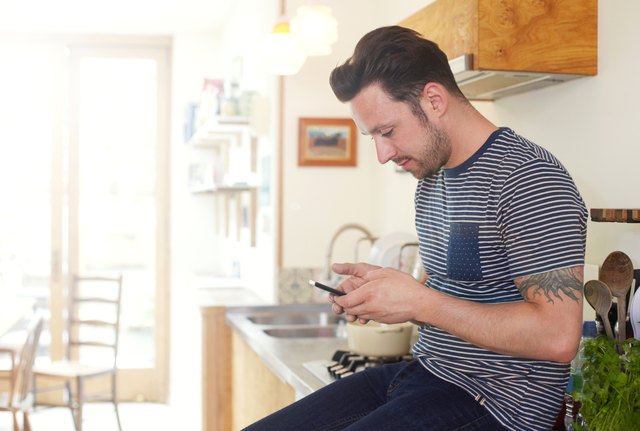 Man texting in kitchen