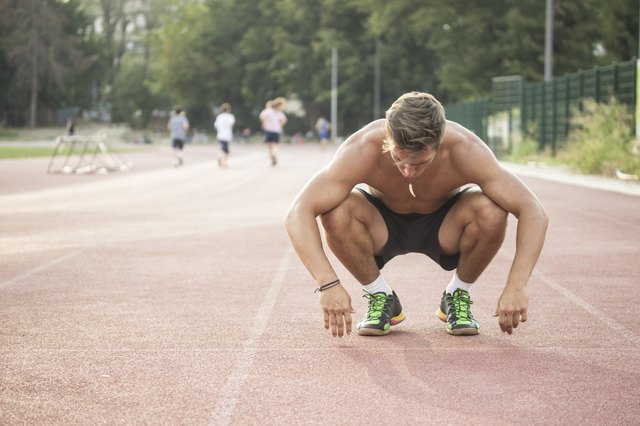 Tired sprinter at start position kneeling.