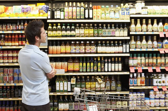 Young man in supermarket looking at bottles on shelves, close-up