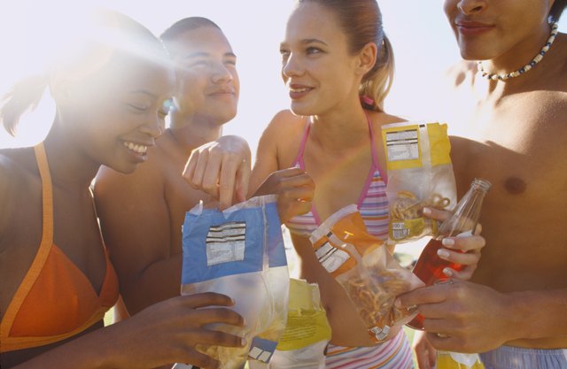 Close-up of two young couples eating crisps and soda