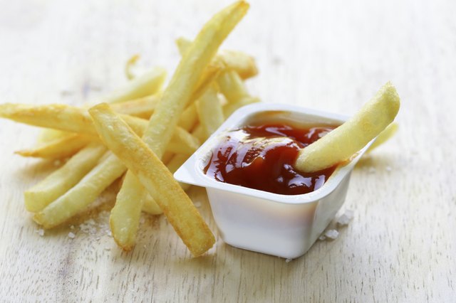 Traditional potatoes French fries with salt on wooden background
