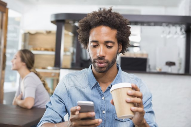 Handsome man sending a text drinking coffee
