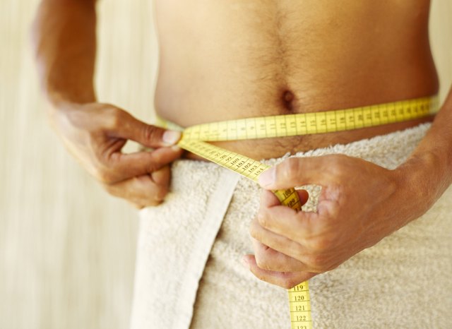 mid section view of a man measuring his waist