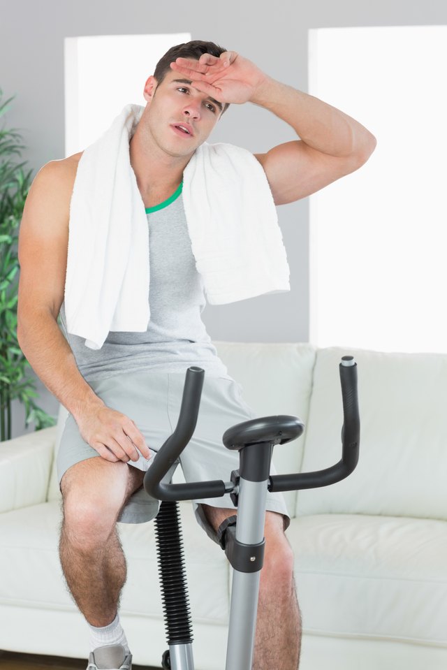Exhausted handsome man training on exercise bike