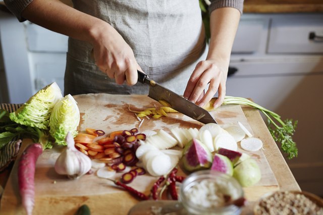 Woman cooking in kitchen with ingredients around her