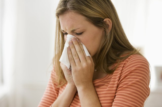 Beautiful young woman blowing her nose
