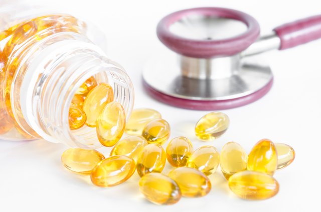 Fish oil capsules spilling out of a bottle and stethoscope