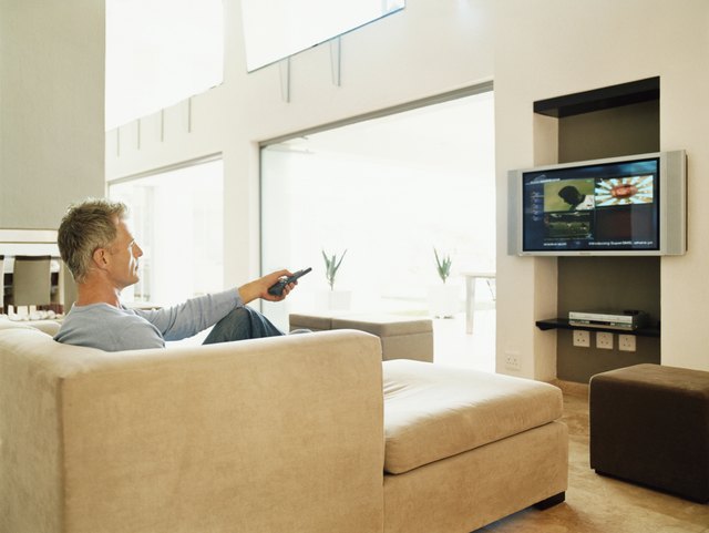 Mature Man Sits Watching TV in a Modern Home Interior