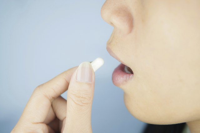Closed up white capsule into mouth