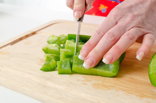Hands of woman cutting green pepper