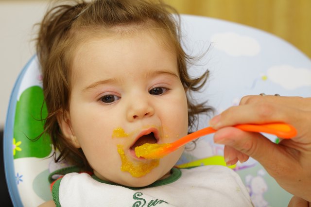 Baby being fed with food around mouth