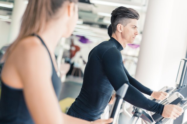 Man and beautiful woman using a stepper in a gym