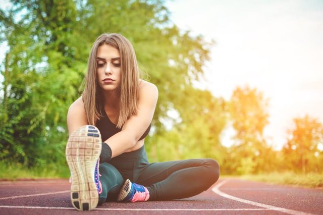 Fit girl practicing stretching exercise at stadium