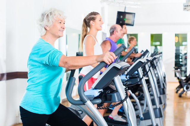Group of people on elliptical trainer exercising in gym