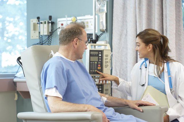 Female doctor operating an IV drip machine with a male patient looking at her