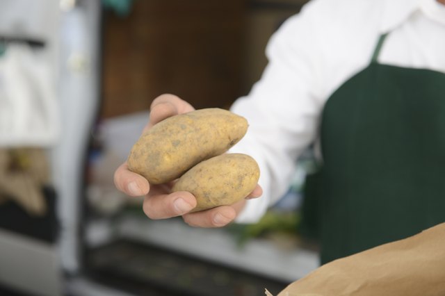 Mature man holding potatoes at market stall