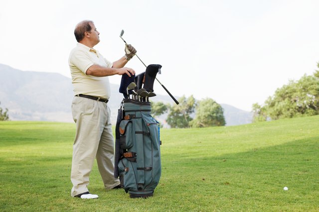 Mature man taking golf club from bag