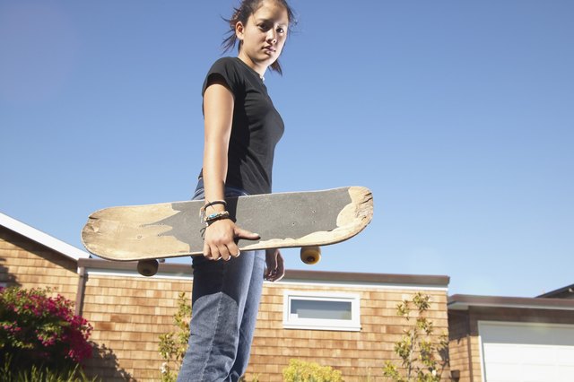 Low angle view of a teenage girl holding a skateboard