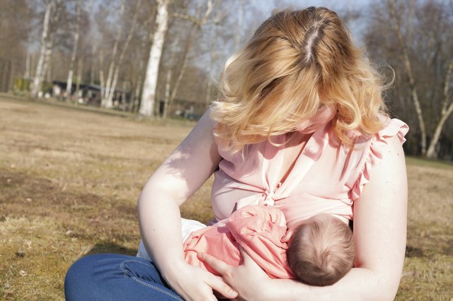 Mother is feeding her baby on the field