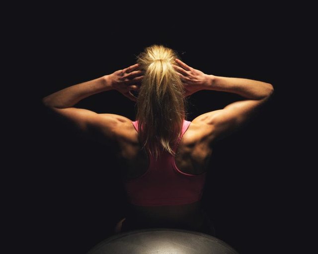 Fitness woman doing stomach crunches while lying on yoga ball