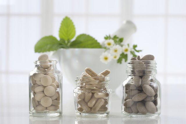 Herbal medicine pills and mortar over bright background