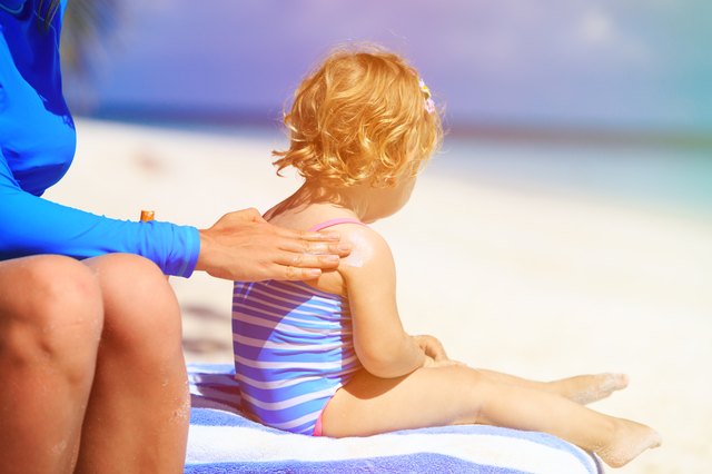 parent applying sunblock cream on child shoulder