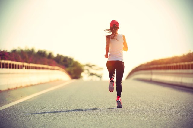 young sports woman runner running on city road