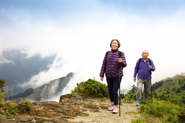 happy asian senior couple hiking on the mountain