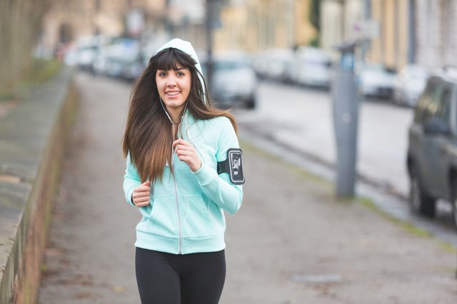 Beautiful young woman jogging alone on city street