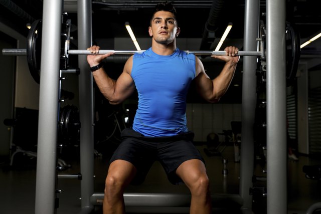 Fitness Trainer doing squats with barbells