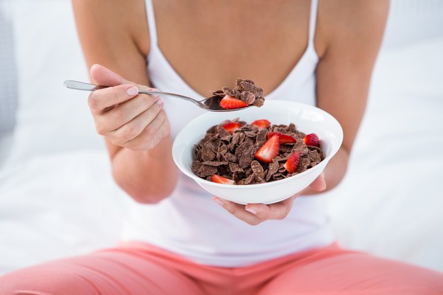 Attractive woman eating cereal in her bed