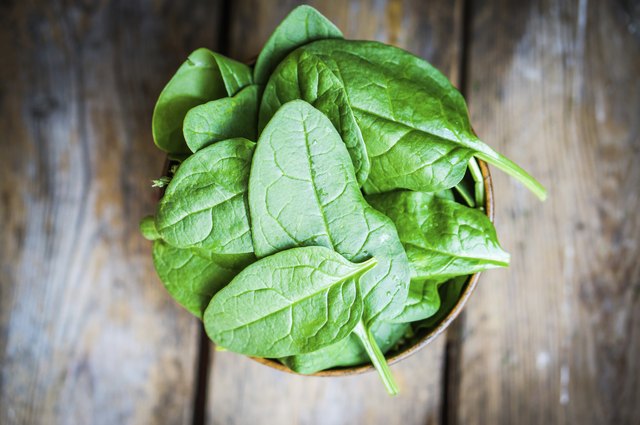 Fresh spinach in a bowl on rustic wooden background