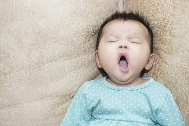 Portrait of a yawning baby girl on leather background
