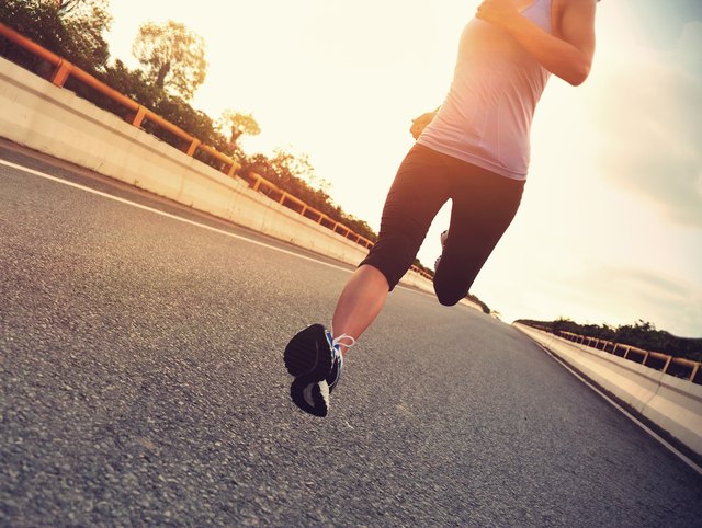 young woman runner running on city bridge road