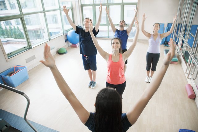 Young people with hands in the air in a yoga class