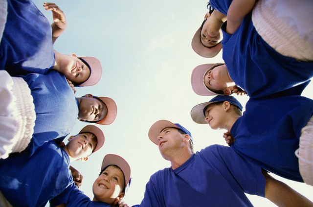 Low angle view of baseball players standing in a huddle with their coach