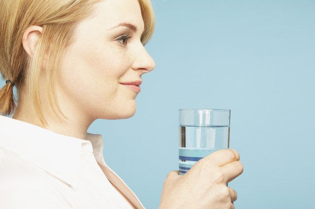 Studio shot of young woman holding glass of water
