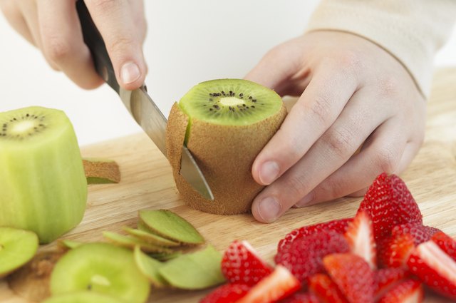 Removing the skin of a kiwi fruit, close up