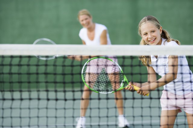 Girl playing tennis with parent