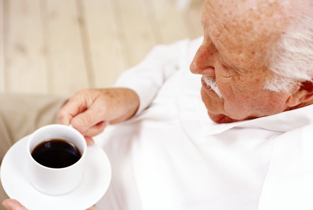 high angle view of an elderly man holding a cup of black coffee