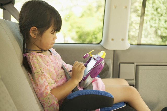 A girl in her car seat playing with an electronic toy