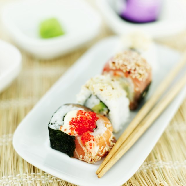 close-up of a tray of assorted sushi rolls served with chopsticks