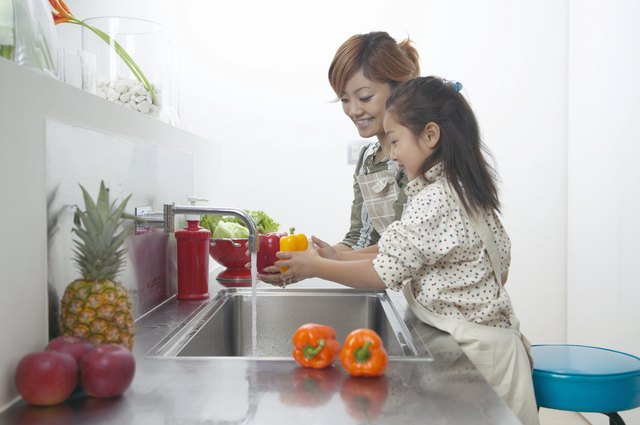 Mother and Daughter Washing Peppers at a Kitchen Sink